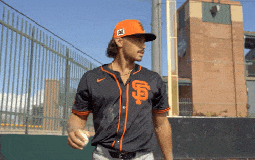 a man wearing an sf jersey holds a baseball in his hand