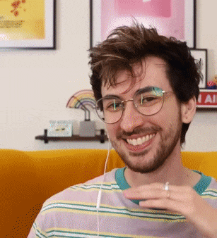 a young man wearing glasses and a striped shirt is smiling for the camera