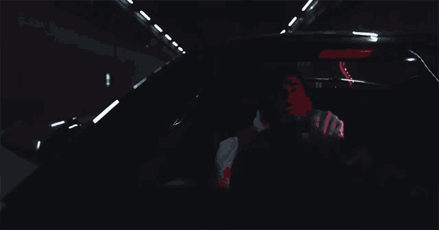a man is sitting in a car with a red light shining on him