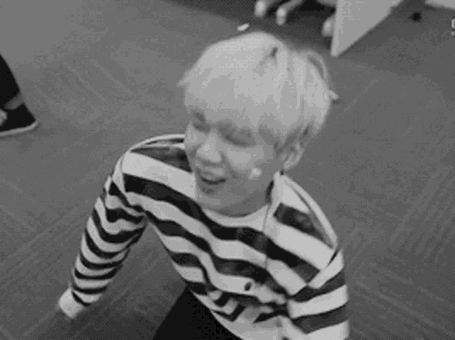 a black and white photo of a young man wearing a striped sweater .