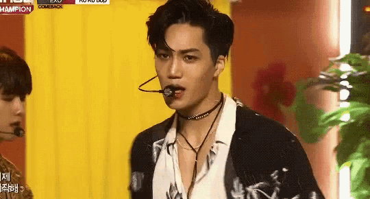 a man wearing a choker and a microphone is standing in front of a yellow door .