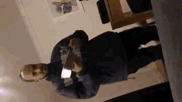 a man in a blue sweater is standing in a living room holding a card .