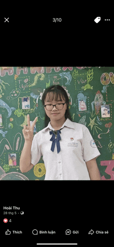 a girl giving a peace sign in front of a green board