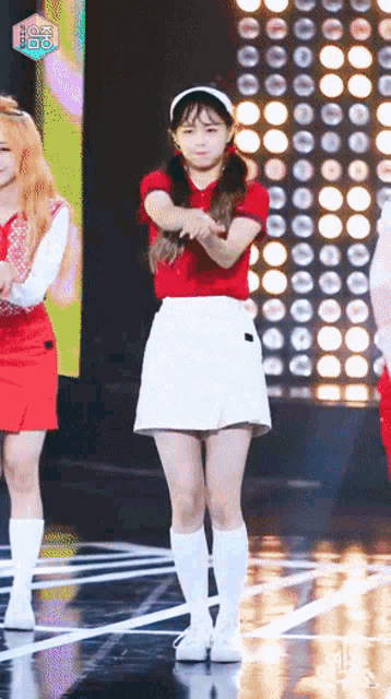 a woman in a red shirt and white skirt is dancing on a stage