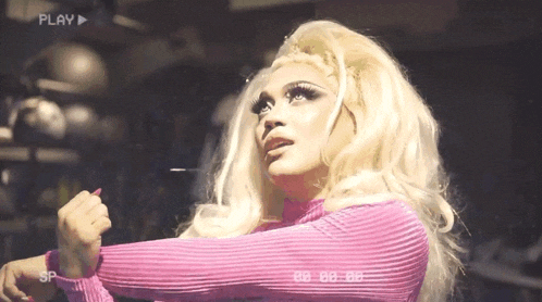 a blonde woman in a pink sweater is stretching her arms