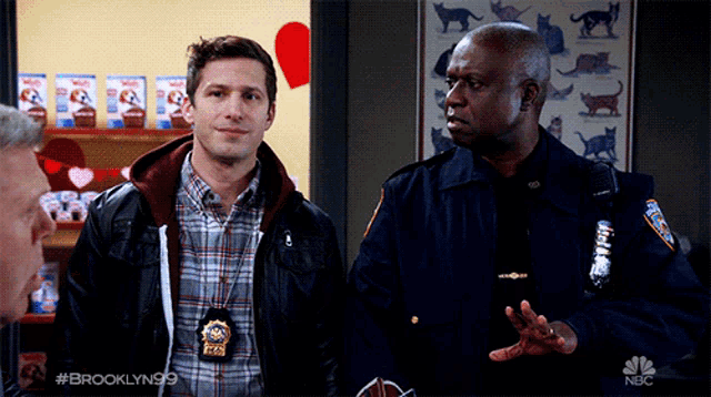 two police officers are standing next to each other in a room with a nbc logo in the corner