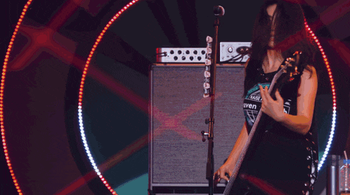 a woman is singing into a microphone while holding a guitar and wearing a shirt with the number 17 on it