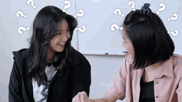 two girls are talking with question marks around them