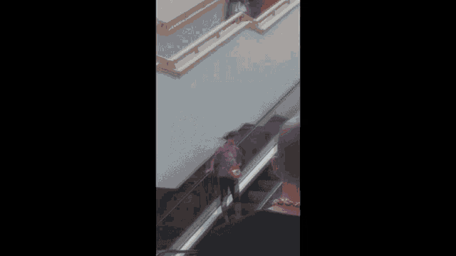 a blurred image of a woman walking down an escalator