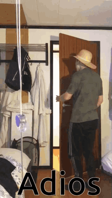 a man in a straw hat is standing in front of a door with the word adios on the bottom