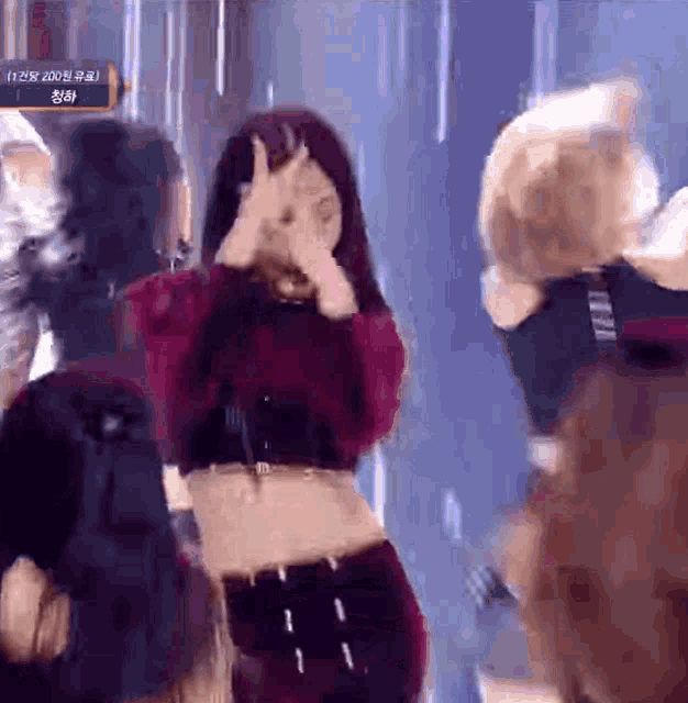 a woman in a red top is covering her face with her hands .