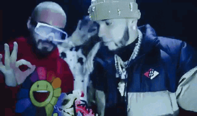 a couple of men are standing next to each other and one of them is wearing goggles .