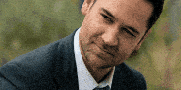 a man in a suit and tie is smiling and looking at the camera