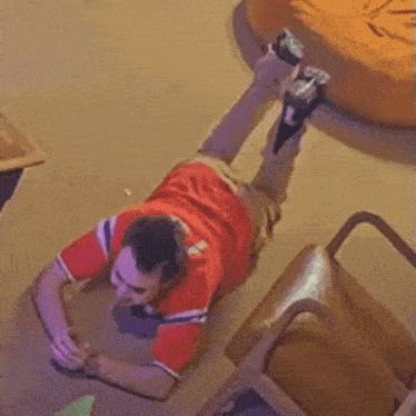 a man in a red shirt is laying down on the floor