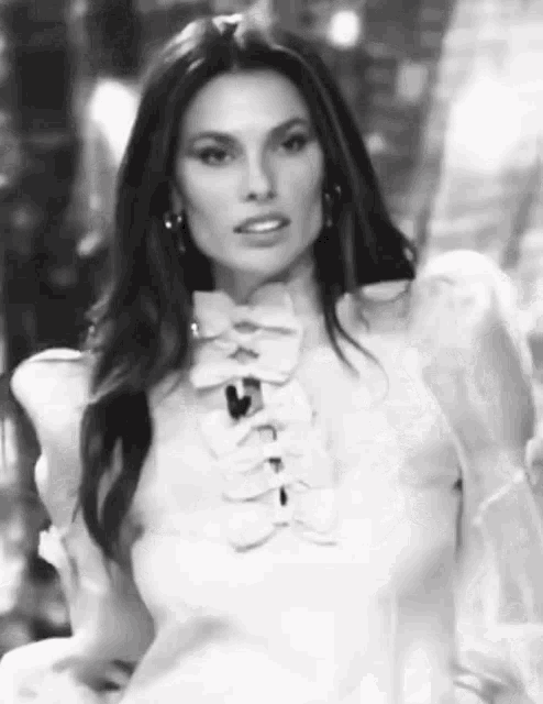 a black and white photo of a woman in a white dress with ruffles .