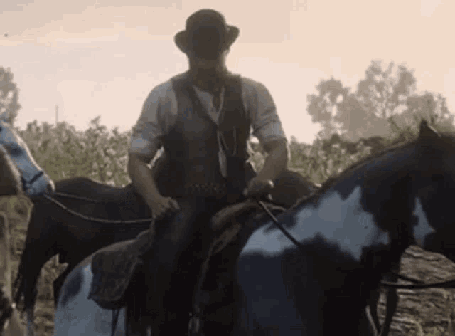a man in a hat is riding a black and white horse in a field .