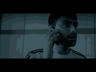 a man with a beard is talking on a cell phone in a dark room