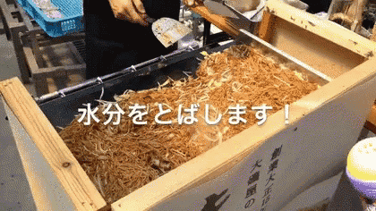 a person is cooking noodles in a wooden box with chinese writing
