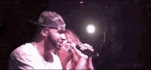 a man and a woman are singing into microphones on a stage in a dark room .