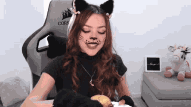 a woman wearing cat ears is sitting in front of a corsair gaming chair