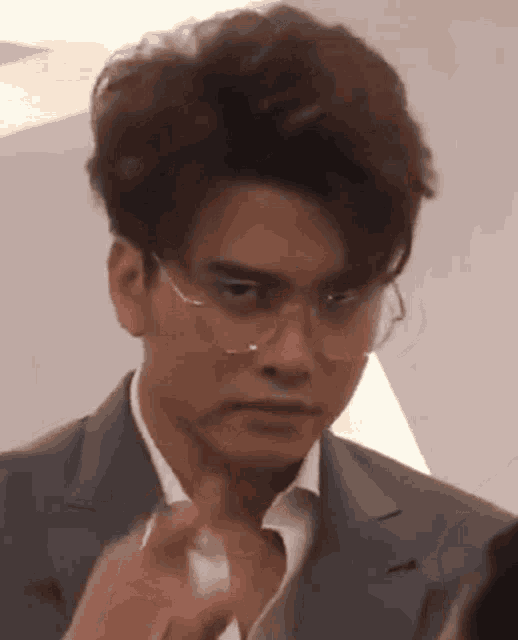 a man wearing glasses and a suit is making a face .