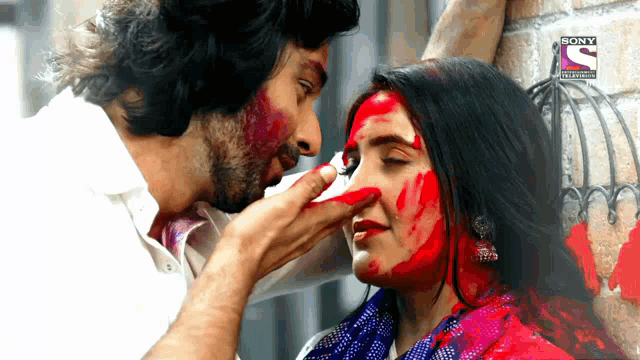 a man is touching a woman 's face with a sony television advertisement in the background