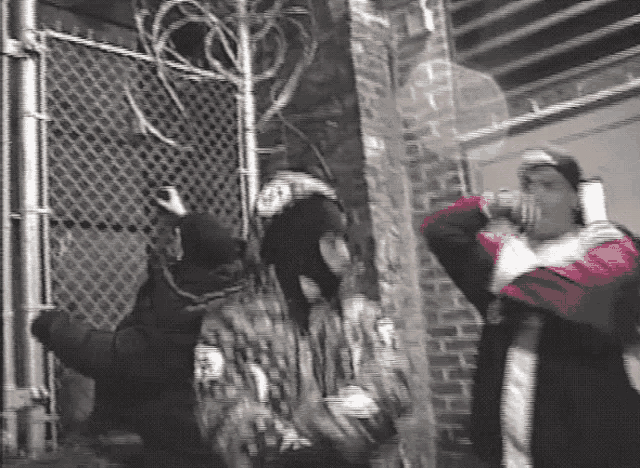 a group of people are standing in front of a fence .