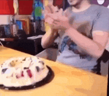 a man is sitting at a table with a birthday cake on it .