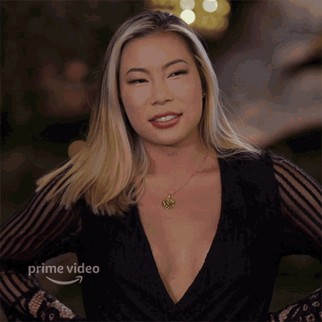 a woman is wearing a black top with a plunging neckline and a necklace that says ' prime video ' on it