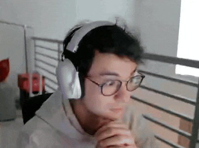 a man wearing headphones and glasses is sitting in front of a computer screen .