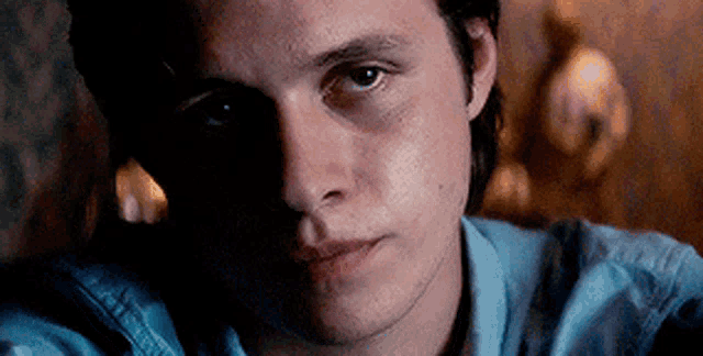 a close up of a young man 's face in a blue shirt .