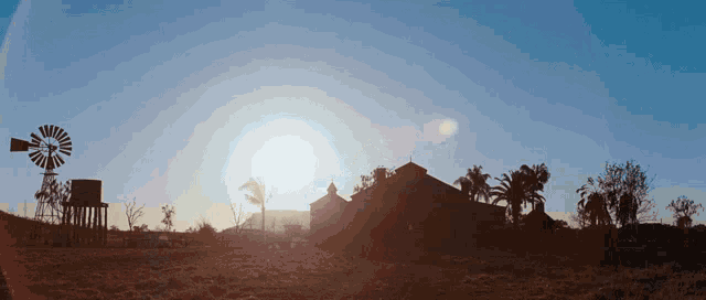 a windmill is silhouetted against a blue sky with the sun shining through it