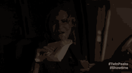 a man is sitting in a dark room holding his nose .