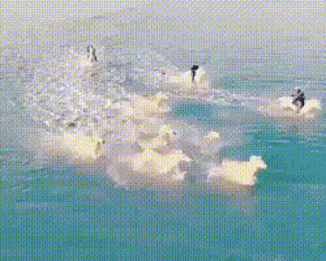 a group of surfers riding a wave in the ocean