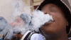 a man in a hat is smoking an electronic cigarette .