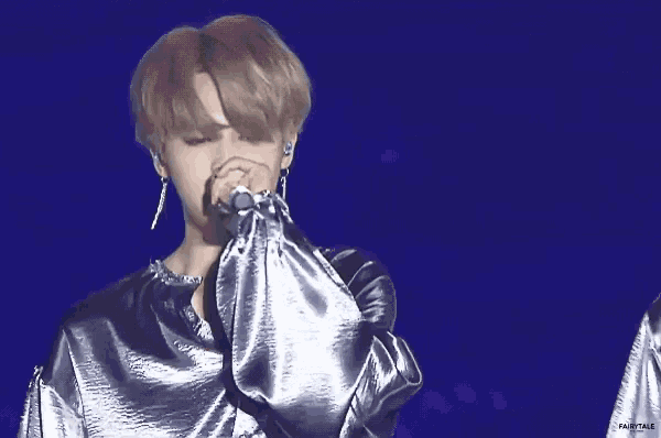 a man singing into a microphone while wearing a blue satin shirt