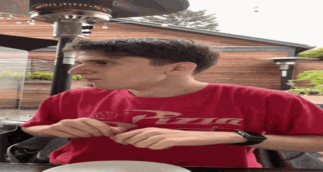 a man wearing a red shirt that says pizza