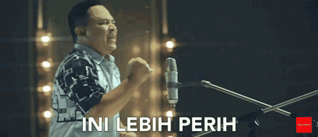 a man singing into a microphone with the words " ini lebih perih " above him