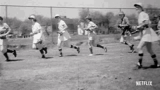 a group of women are running on a baseball field .