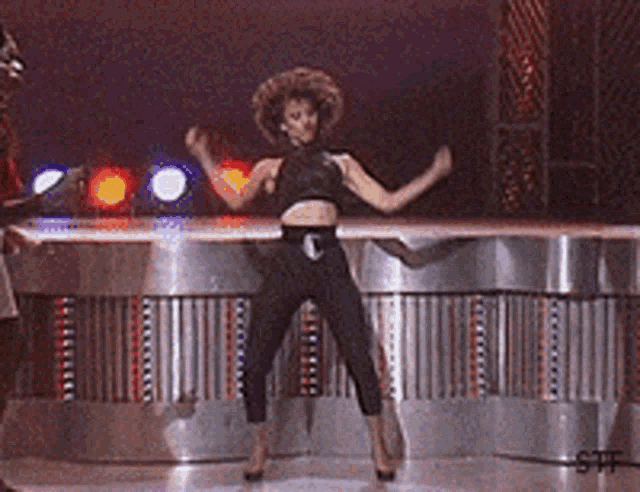 a woman in a crop top and pants is dancing