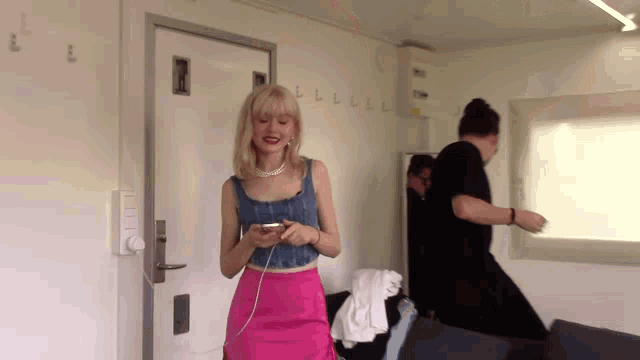 a woman in a pink skirt is looking at her cell phone