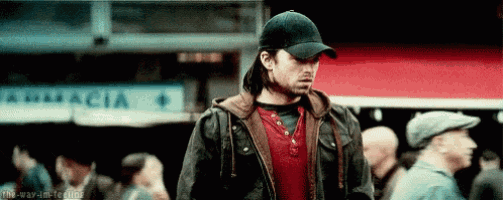 a man wearing a baseball cap and a jacket is standing in a crowded street .