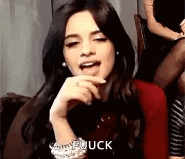 a woman is sitting on a couch making a funny face with her hand on her chin .