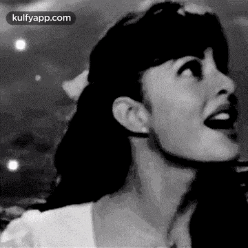 a black and white photo of a woman with her mouth open and looking up .