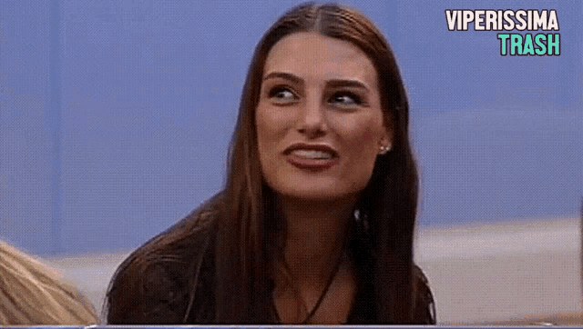 a woman is smiling in front of a blue wall with the words viperissima trash above her