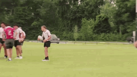 a group of people are playing a game of rugby on a field . one of the players has the number 2 on his jersey .