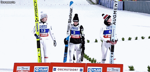 skiers stand on a podium sponsored by plan oberstdorf and fischer