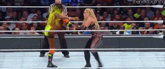 two women are wrestling in a wrestling ring while a referee watches .