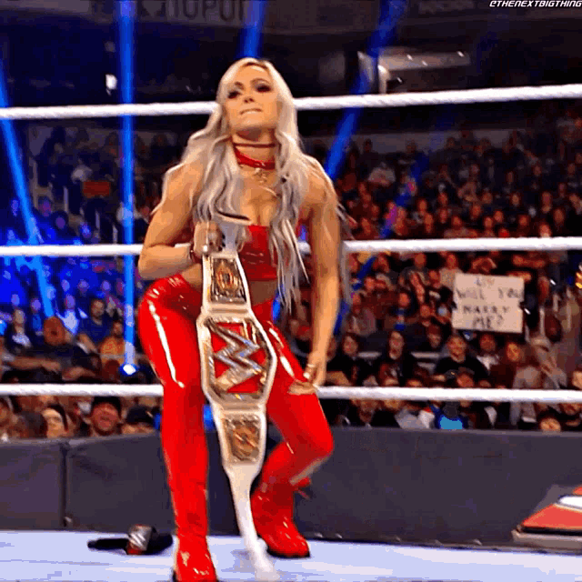 a woman in a wrestling ring with a sign that says " it 's will you make me "