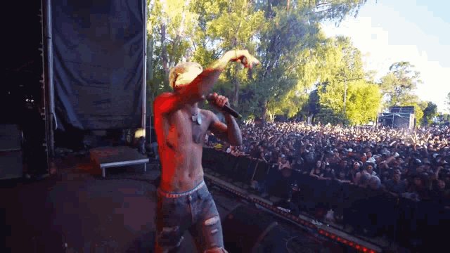 a shirtless man is singing into a microphone at a concert